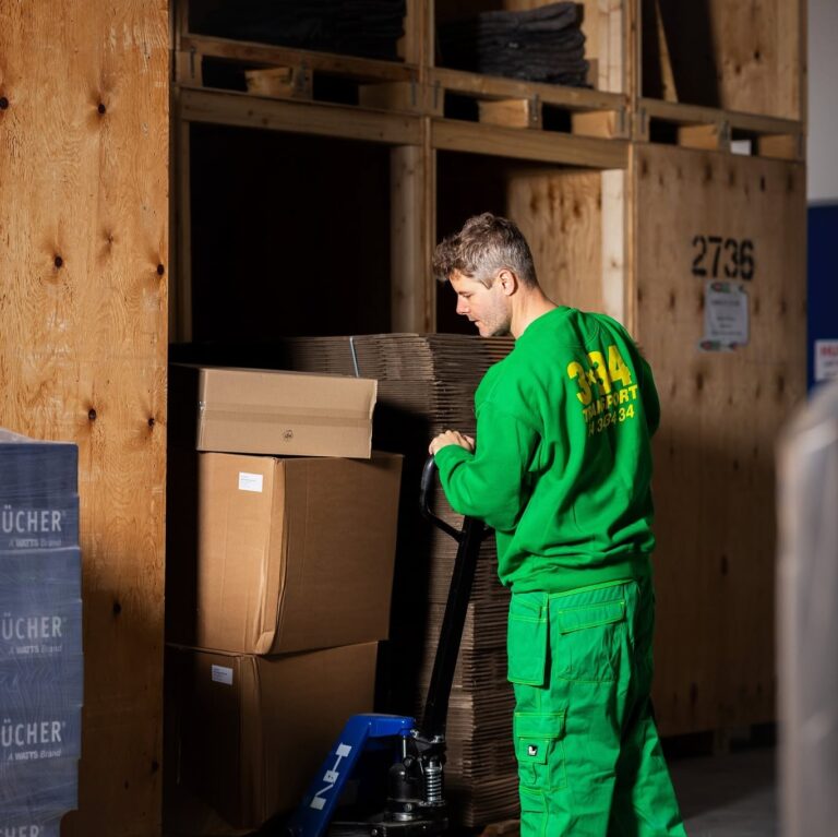 3x34-medarbejder med palleløfter blandt flyttekasser